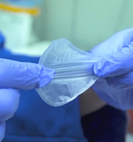 Mãos com luvas manipulam material plástico