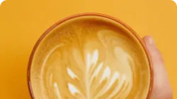 Ch&aacute;vena de caf&eacute; latte art sob fundo laranja